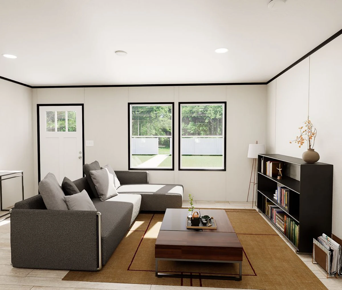 3b00db7c-04e0-44d8-8ac0-32a250dc8f24 A modern living room with a gray sectional sofa, a wooden coffee table, a black bookshelf, and large windows looking out onto a green backyard.