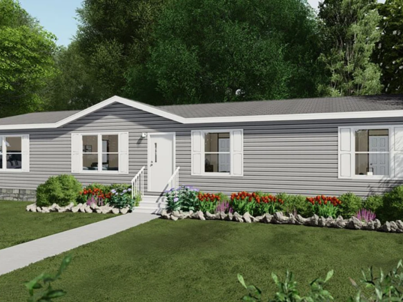 A single-story manufactured home with gray siding, white trim, and a small front porch, surrounded by a landscaped yard with flowers and shrubs.