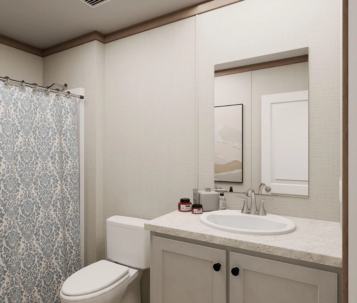 Modern bathroom with a shower featuring a blue patterned curtain, a white toilet, a sink with a marble countertop, and a wall-mounted mirror above the vanity.
