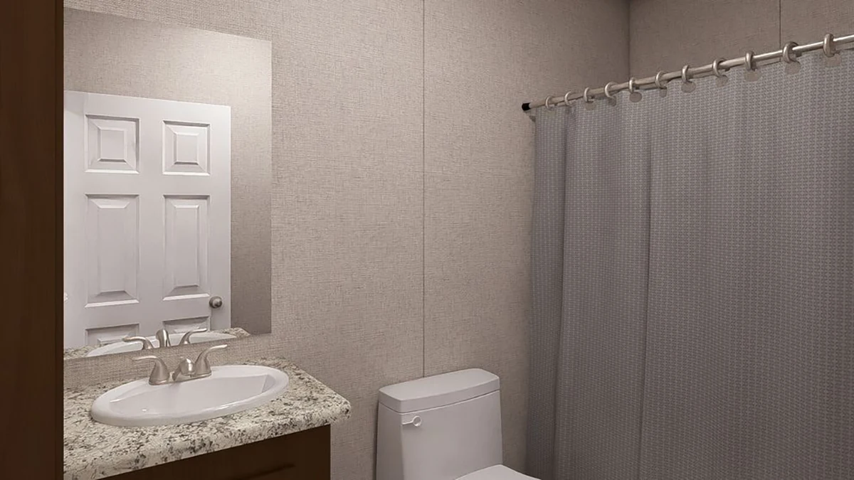 A bathroom with a sink, countertop, toilet, mirror, and a shower with a gray curtain.