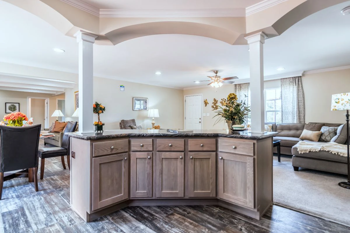 Open-concept living space featuring a kitchen island with cabinets, dining area with table and chairs, and a living room with sofas and decor.