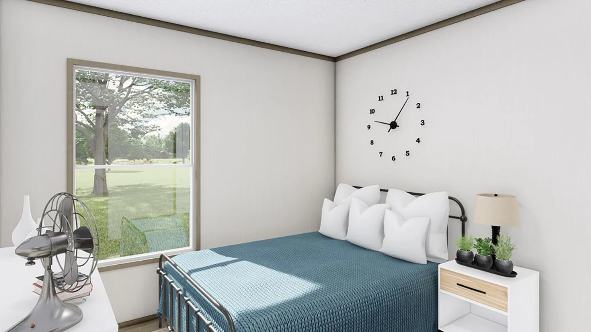 A bedroom with a bed covered in a blue blanket, a nightstand with a lamp and plant, a desk fan, books, and a window overlooking a green lawn. A clock is on the wall above the bed.