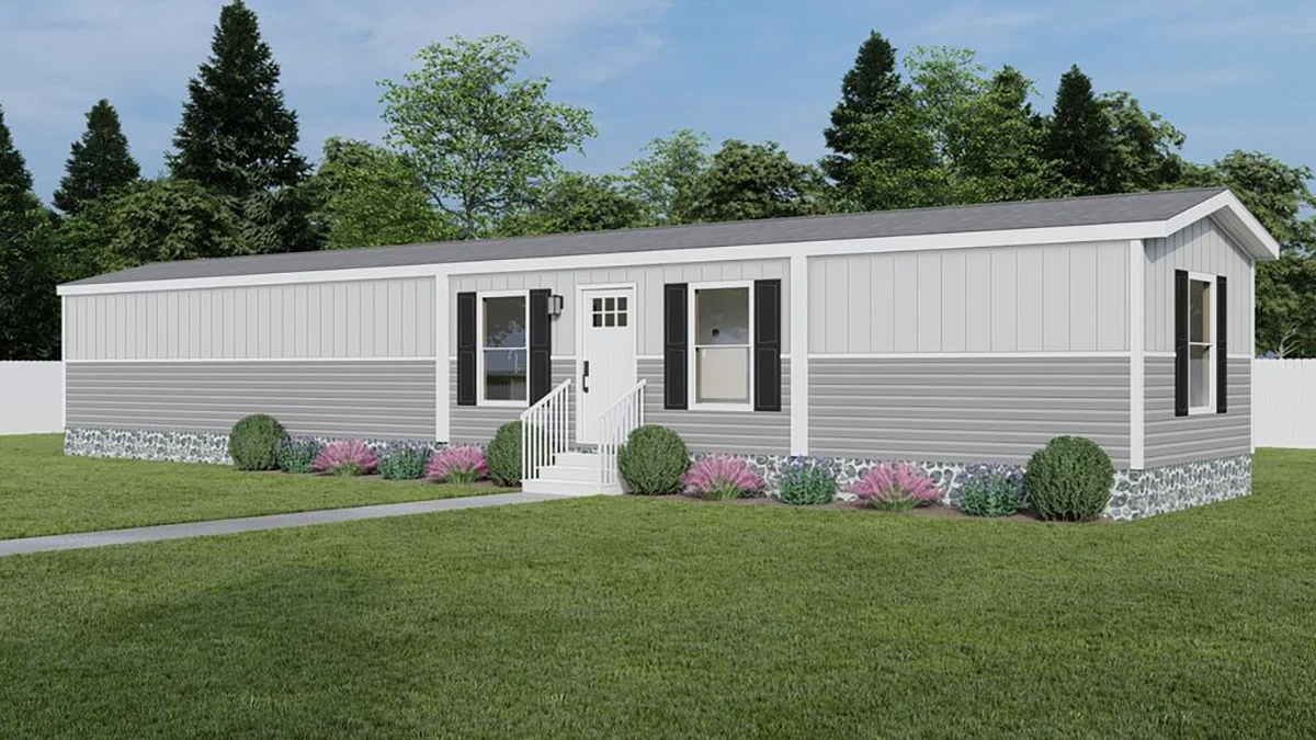 A single-story, gray manufactured home with white trim, front steps, and simple landscaping, set on a grassy lawn with trees in the background.