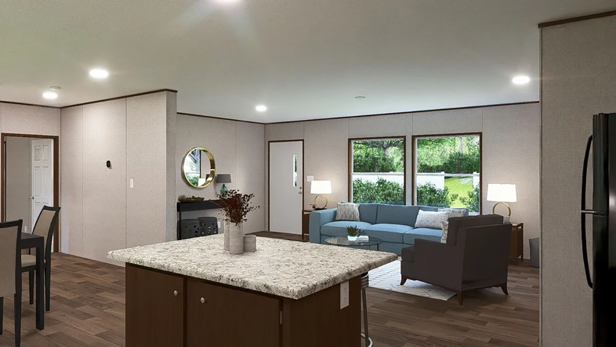 Open living area with kitchen island, dining space, and seating area featuring a sofa, armchair, lamps, and large windows overlooking greenery.