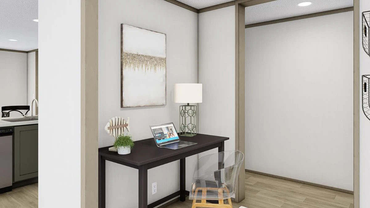 A home office setup with a dark desk, laptop, lamp, decor items, clear chair, and wall art in a corner next to an open doorway.