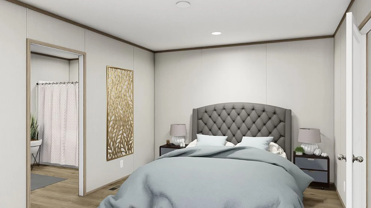 A modern bedroom with a gray tufted headboard, two bedside tables with lamps, and an adjoining bathroom visible through an open door.