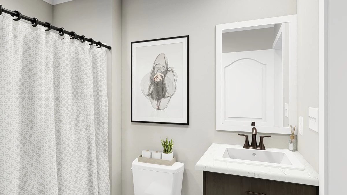 Modern bathroom with a patterned shower curtain, framed abstract art above the toilet, a small plant, and a white sink with a dark faucet and mirror.