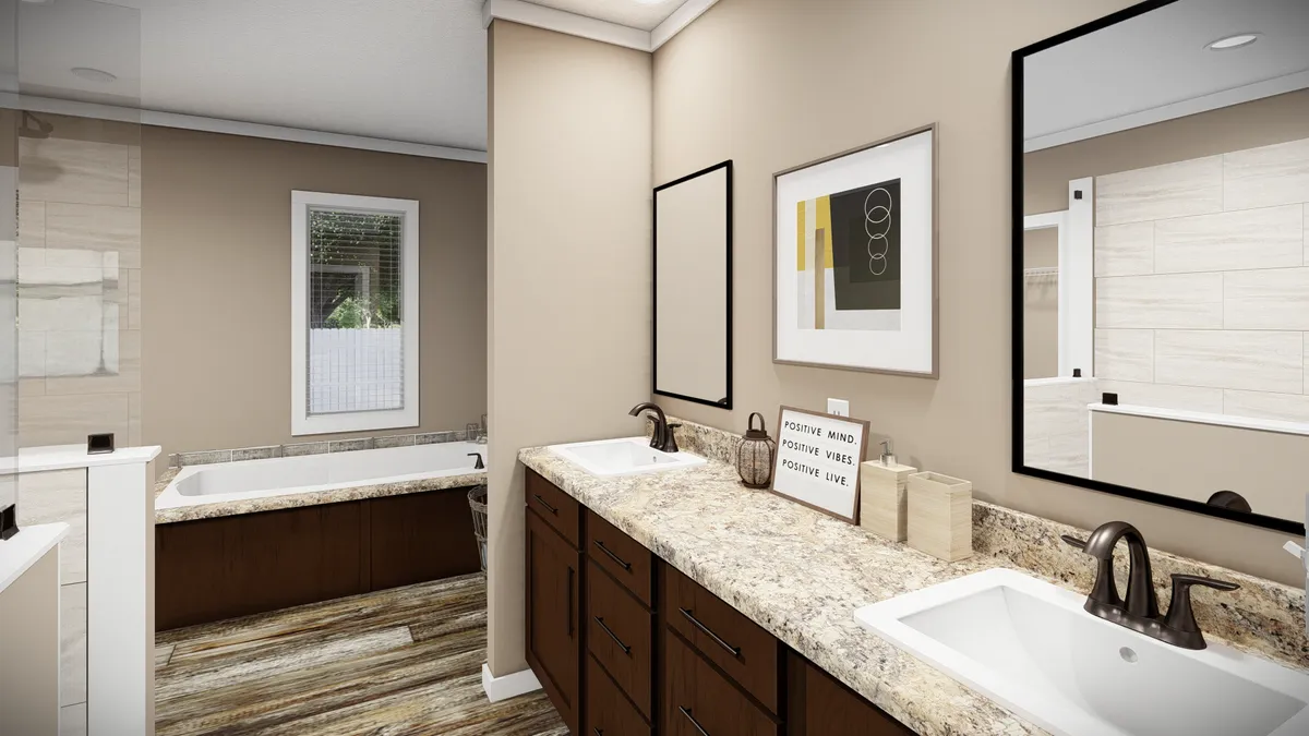 Modern bathroom with double sinks, granite countertops, brown cabinets, a bathtub, framed mirrors, neutral walls, and decorative art above the counter.