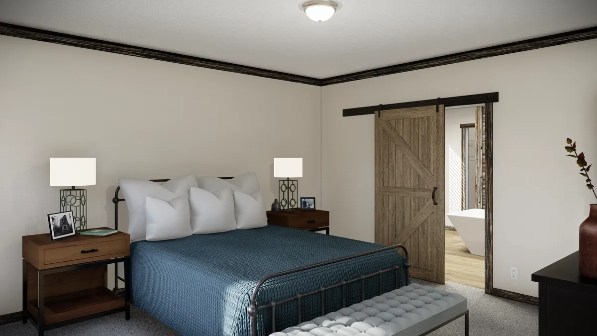 64b1b705-713b-4b99-a3f6-7ec6645fedb8 A bedroom with a metal bed frame, blue bedding, two nightstands with lamps, a tufted bench, and a sliding barn door leading to a bathroom.