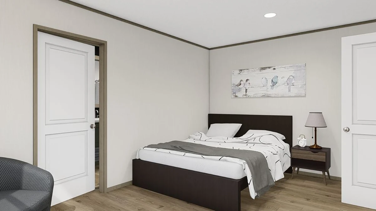 A small bedroom with a bed, nightstand, lamp, wall art of birds, light-colored walls, wood flooring, and two white doors.