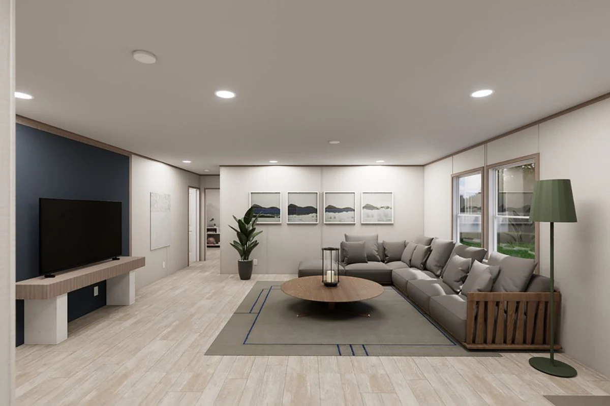Modern living room with a large gray sectional sofa, round wooden coffee table, TV on a stand, floor lamp, indoor plant, and framed artwork on the wall.
