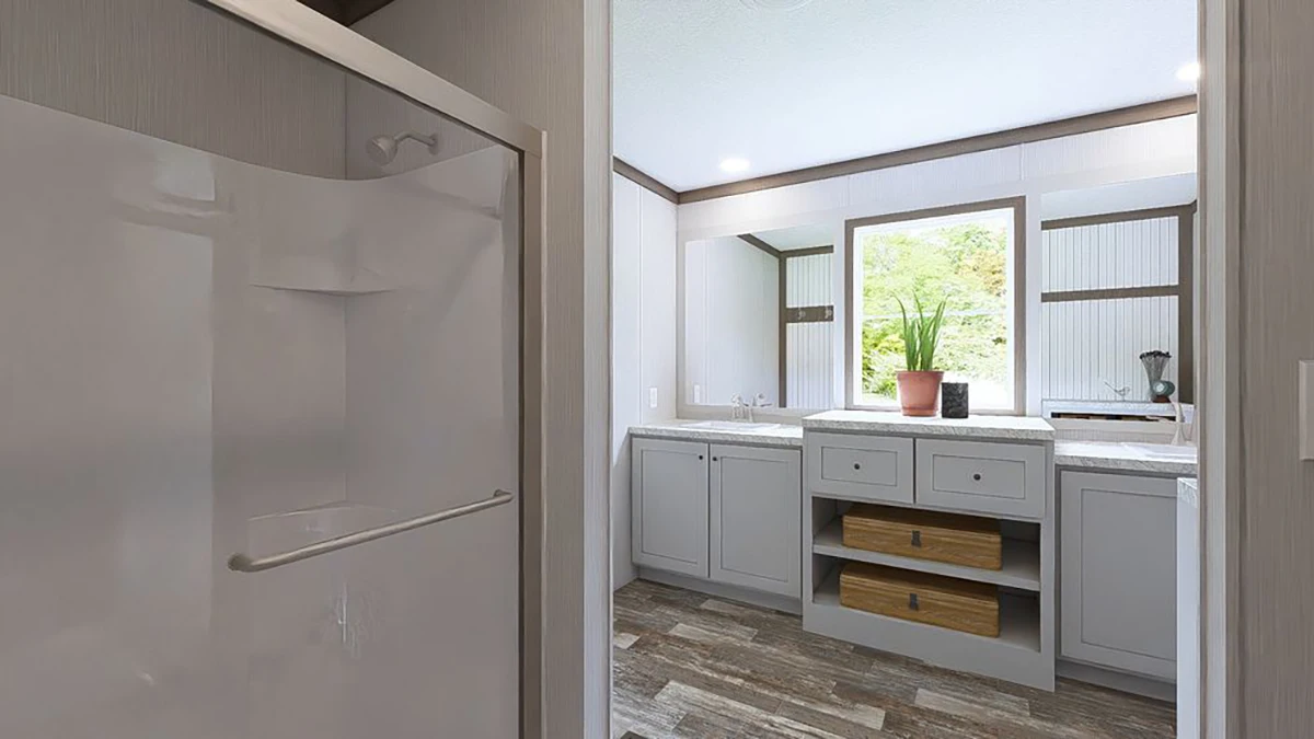 View of a modern bathroom with a glass shower on the left, a double-sink vanity with drawers, a large mirror, and a potted plant by a window.