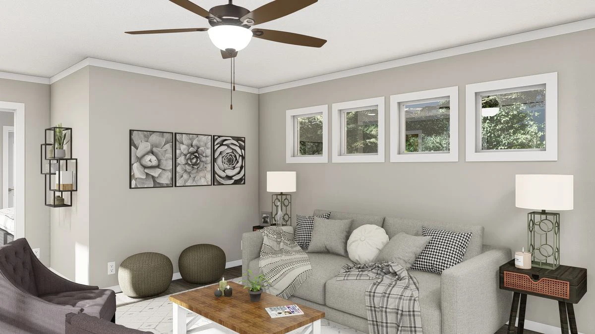 A modern living room with a gray sofa, patterned pillows, a wooden coffee table, wall art, two lamps, and four rectangular windows above the couch.