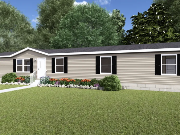 A beige, single-story manufactured home with black shutters, white trim, front steps, and a small flower garden, surrounded by green grass and trees under a blue sky.