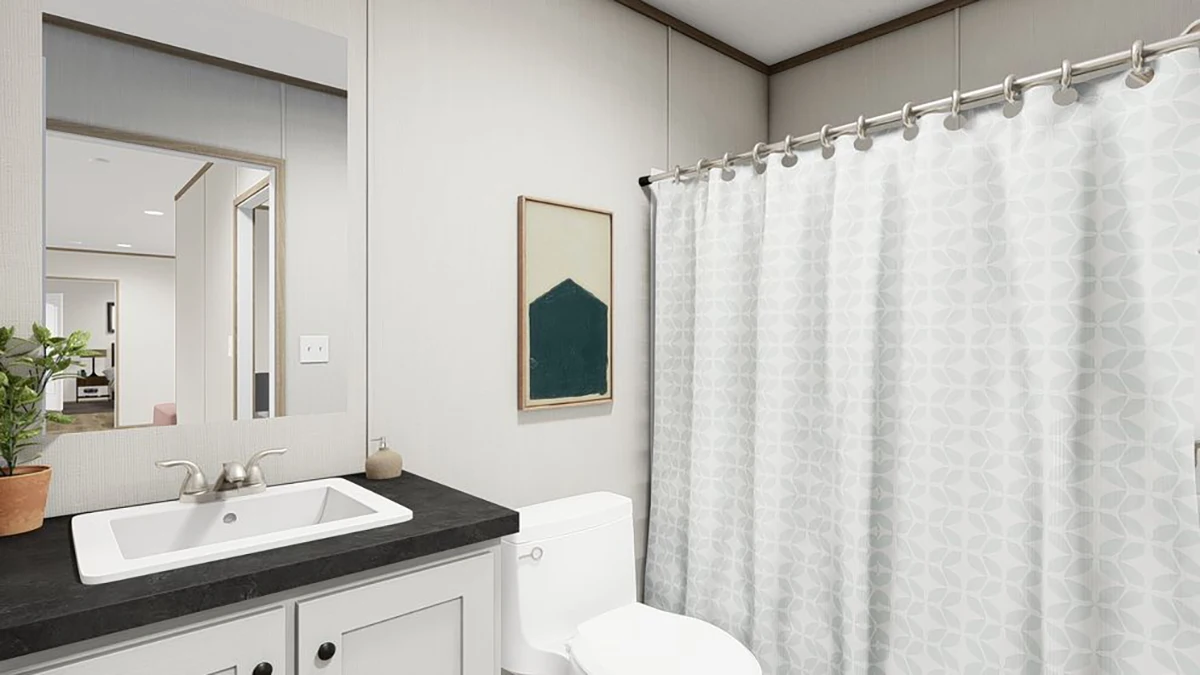 759680c8-7382-4ea8-84db-d2b90108c778 Modern bathroom with a white sink, black countertop, toilet, patterned shower curtain, wall art, potted plant, and a large mirror reflecting another room.