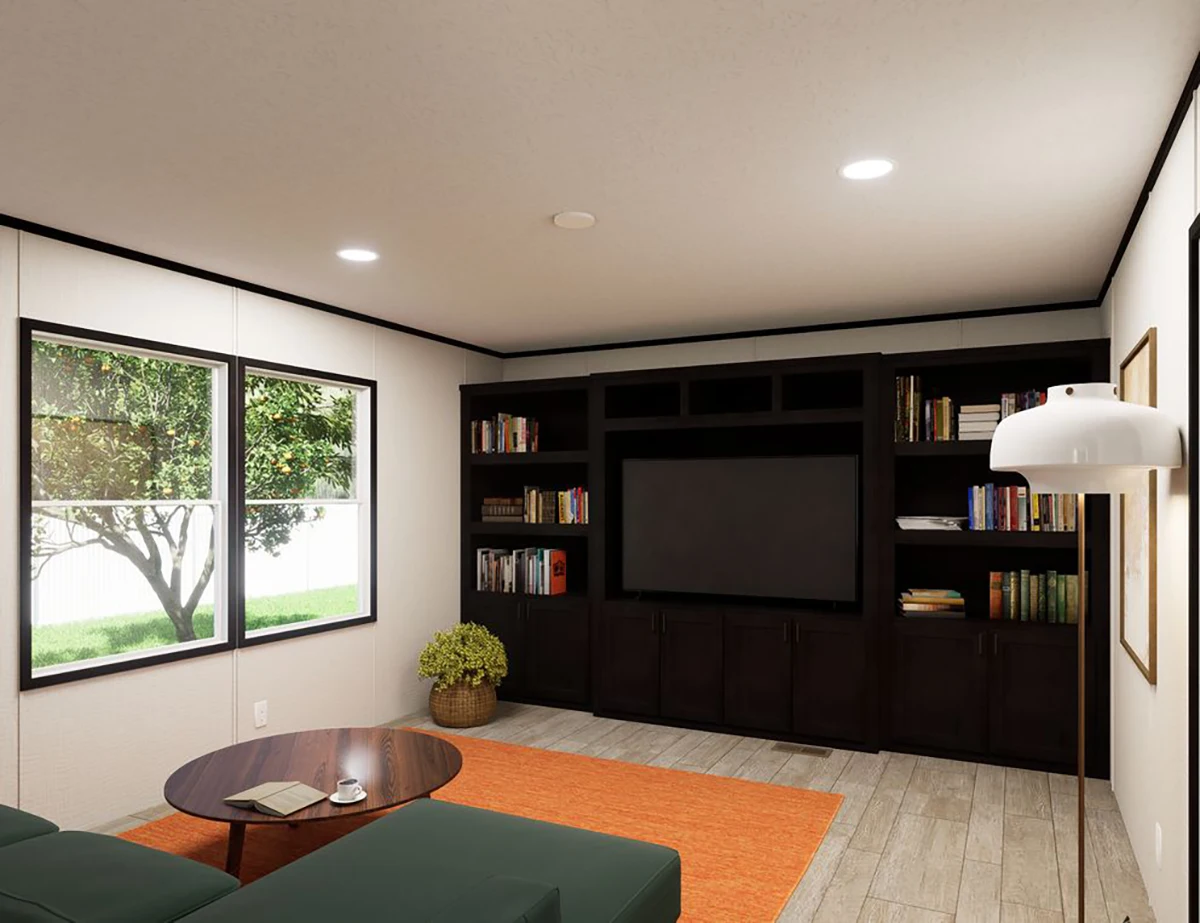 75ed3d65-c591-498b-a834-a81f36dcb167 Modern living room with a large black entertainment center, bookshelves, wall-mounted TV, green sectional sofa, round coffee table, orange rug, and windows overlooking a yard.