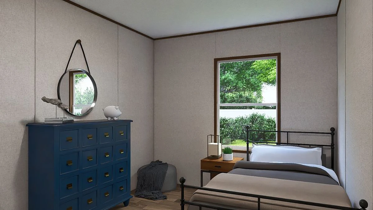 A neatly arranged bedroom with a single bed, a blue dresser with a mirror above it, a nightstand with a lamp, and a window showing greenery outside.