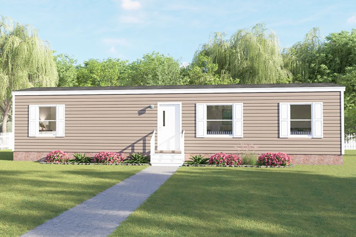 A single-story beige manufactured home with white shutters, a central front door, small front steps, and simple landscaping on a grassy lawn.