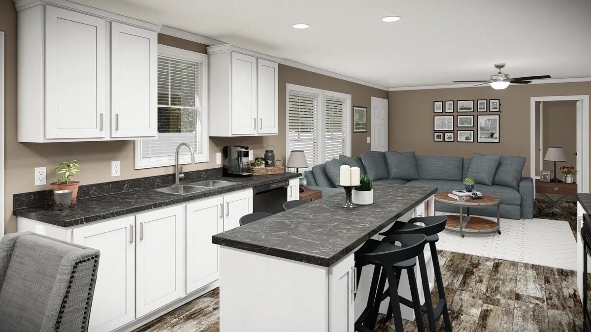 7e44e7de-7534-4a34-b63d-e4ad8b1adb72 Modern open-concept kitchen and living room with white cabinets, black countertops, a large island with stools, gray sectional sofa, and wall art.