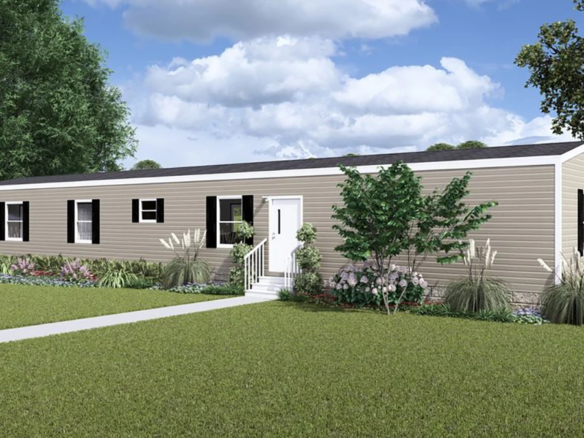 A beige single-wide manufactured home with white trim, surrounded by a lawn, landscaping, and a white picket fence under a partly cloudy sky.