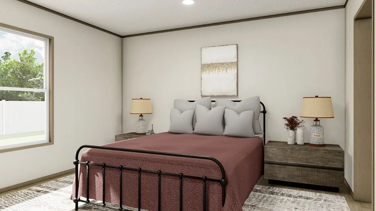 A bedroom with a metal bed frame, maroon bedspread, two bedside tables with matching lamps, a window, and a neutral wall with a painting above the bed.