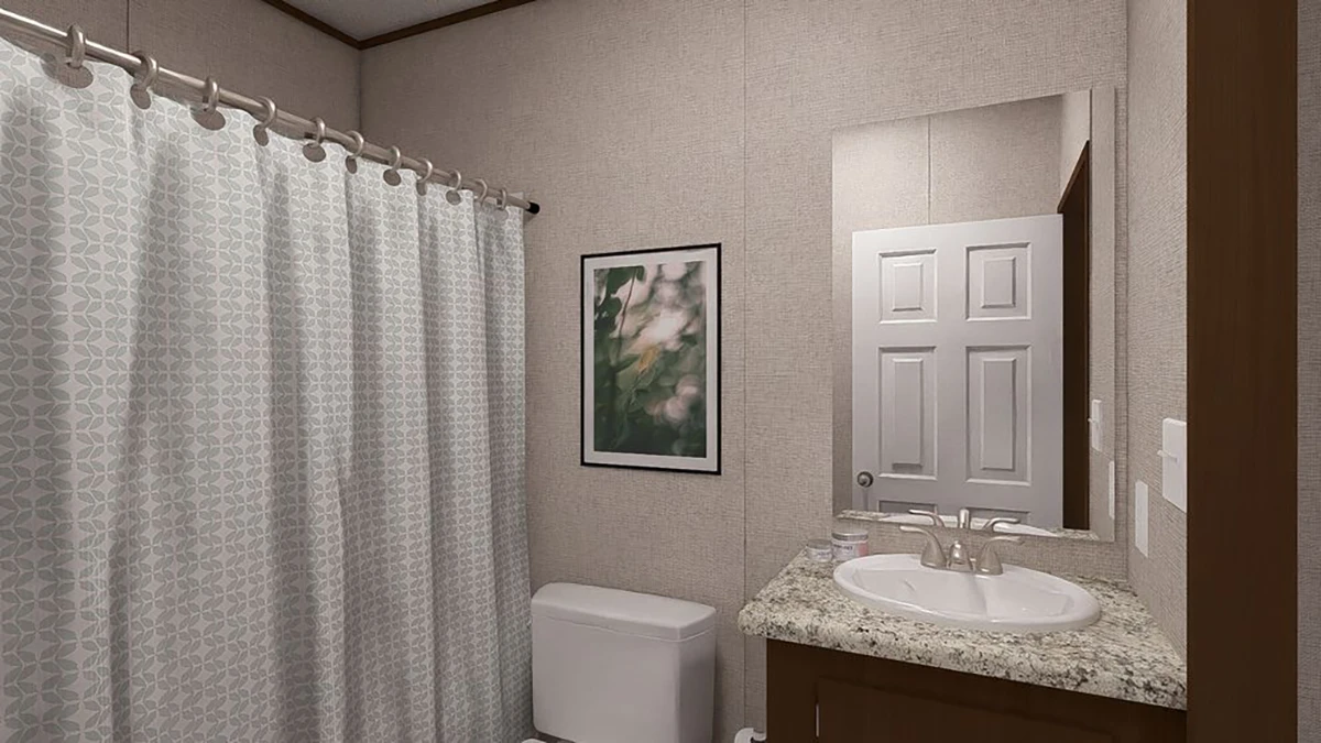 A bathroom with a shower curtain, toilet, framed picture, granite countertop with sink, and a mirror above the sink.
