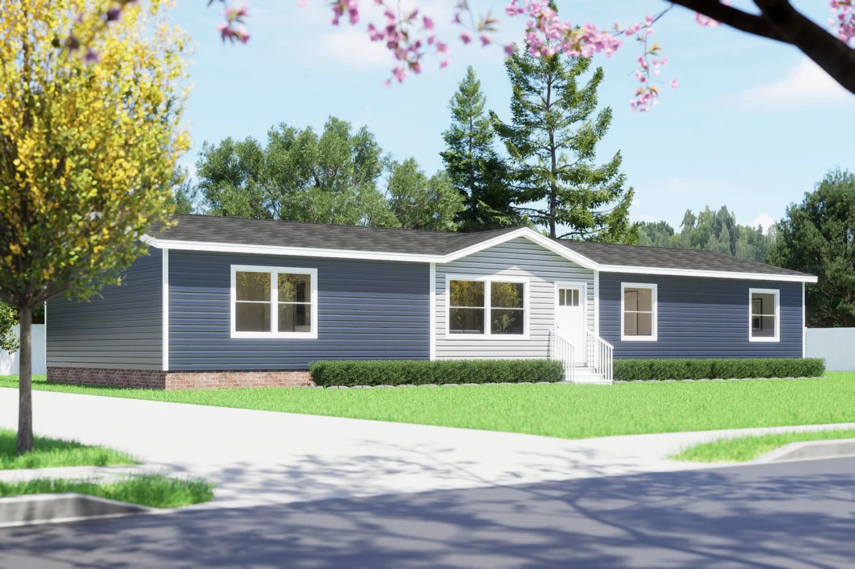 85510d14-f5bb-4a10-9212-82f855487d49 A single-story blue manufactured home with white trim, multiple windows, and a front entrance, surrounded by green grass and trees under a clear sky.