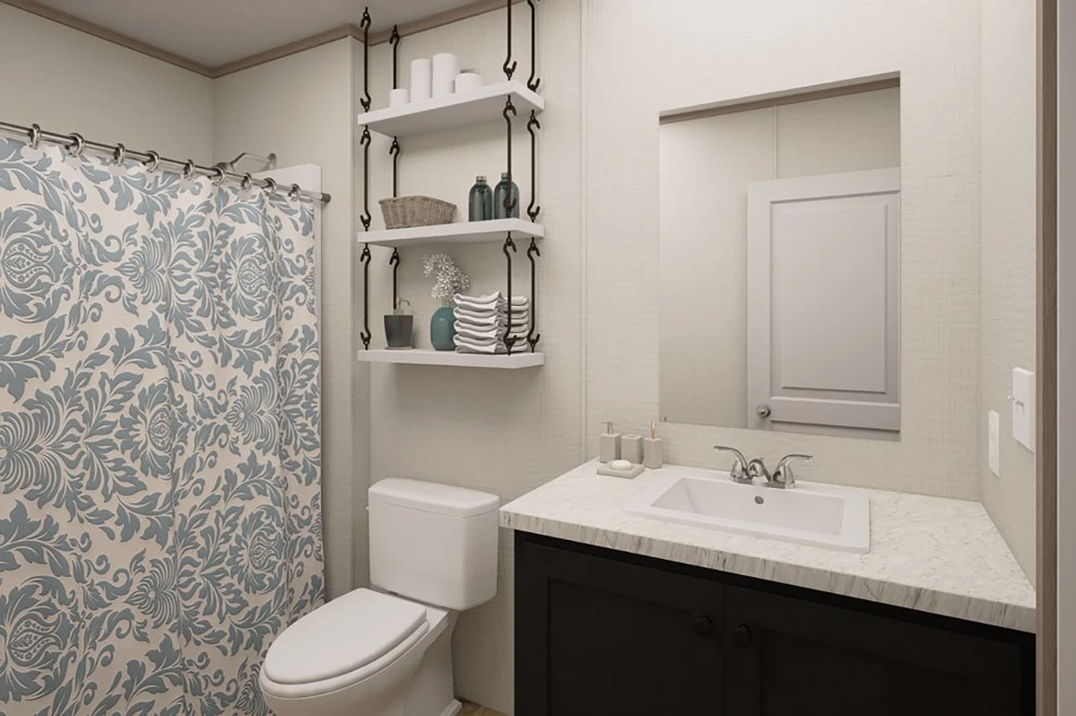 87fc38af-100b-4e2b-9c92-0a3d62c98f20 Bathroom with a white toilet, dark vanity, sink, mirror, wall shelves with towels and decor, and a blue-patterned shower curtain.