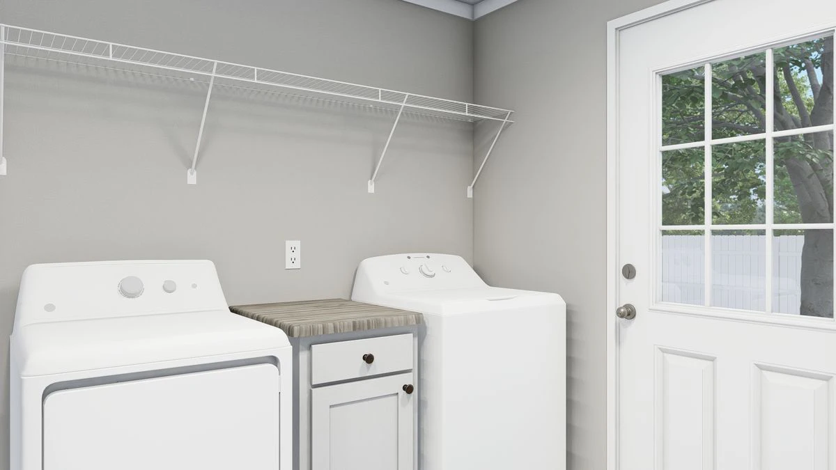 A laundry room with a washing machine, dryer, countertop, small cabinet, wire shelf, and a door with a window showing trees outside.