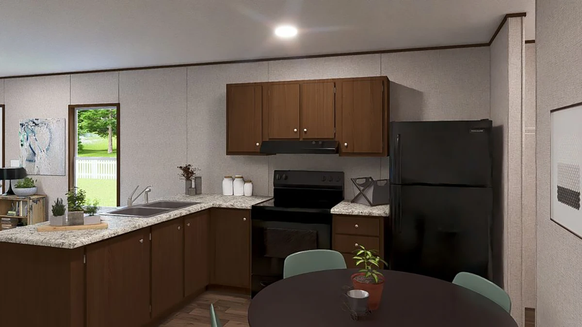 A modern kitchen with brown cabinets, black appliances, granite countertops, and a small round dining table with green chairs and a potted plant.