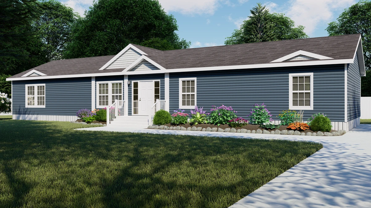 A single-story blue manufactured home with white trim, front steps, and landscaped garden beds, set on a grassy lawn with a concrete walkway.