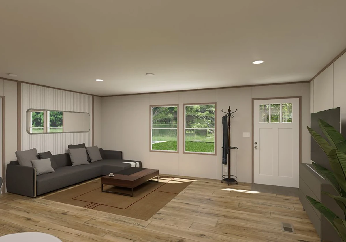 A modern living room with a gray sectional sofa, coffee table, flat-screen TV, plant, and coat rack, featuring wood flooring and large windows showing greenery outside.