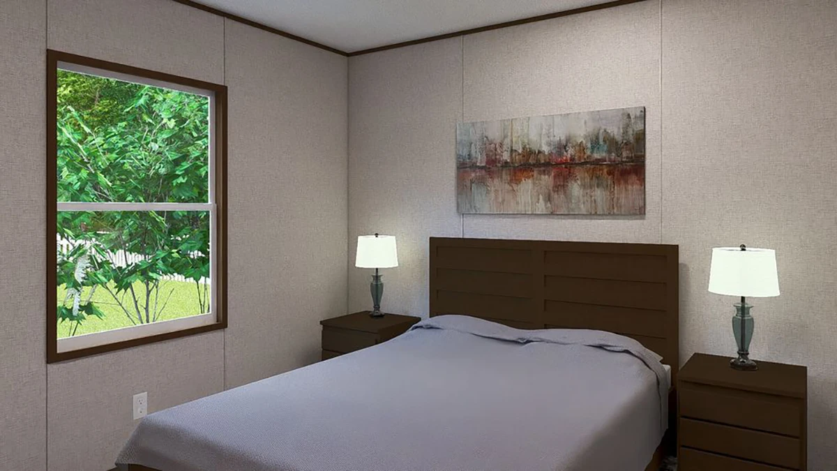 A bedroom with a bed covered in a gray blanket, two bedside tables with lamps, a window showing green trees, and abstract wall art above the headboard.