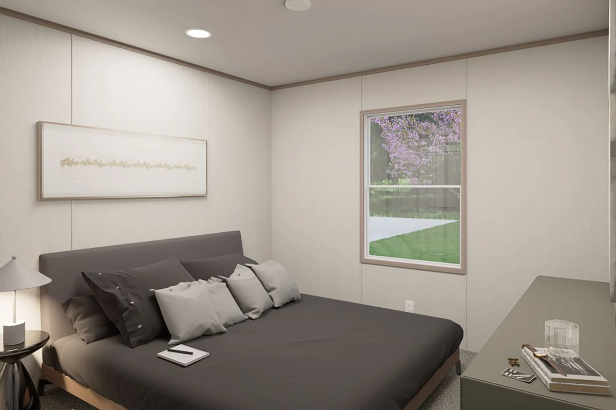 9348e450-9987-4b5e-a99a-235f52684379 A minimalist bedroom with a low-profile bed, dark bedding, a nightstand with a lamp, a desk with items, and a window overlooking a green yard with a blooming tree.