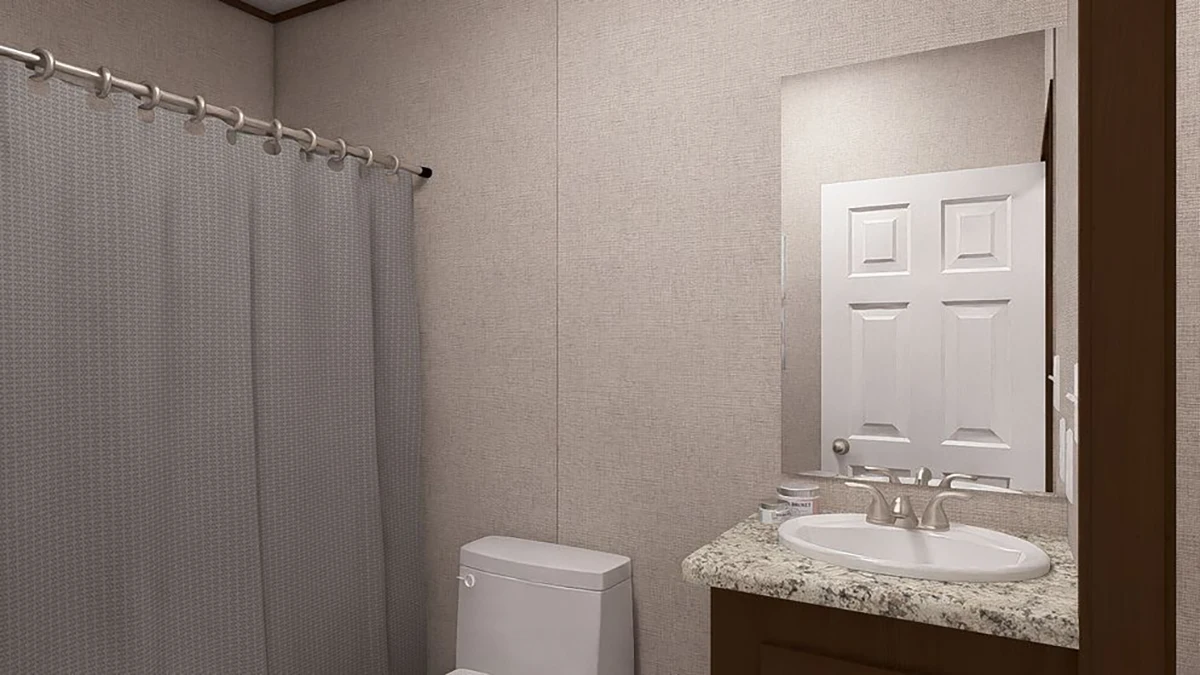 Bathroom with a gray shower curtain, white toilet, and a sink with a marble countertop beneath a large mirror reflecting a door.