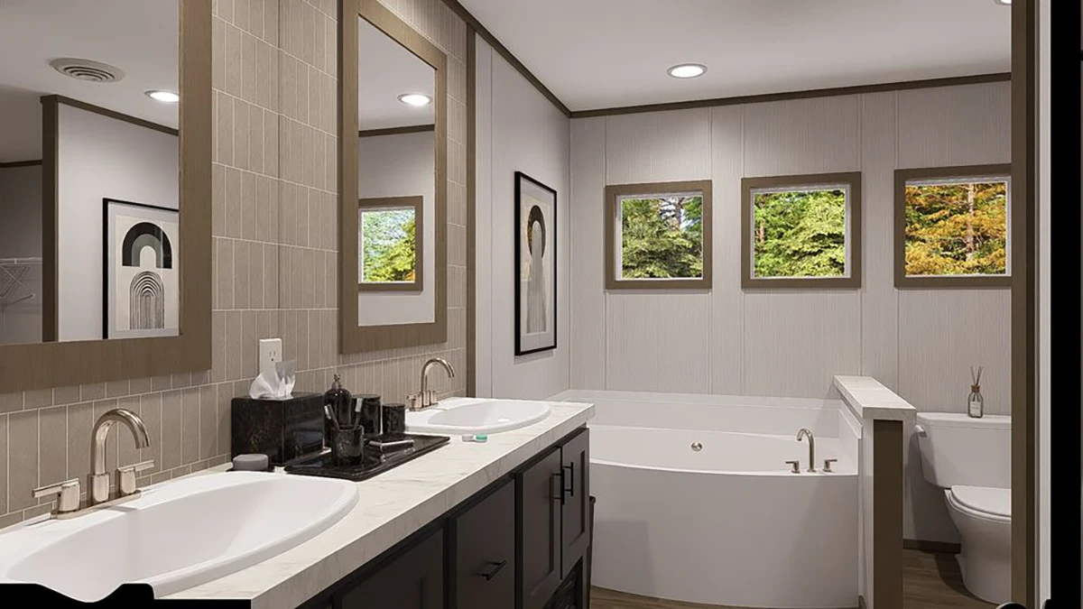 Modern bathroom with double sinks, a large bathtub, toilet, wall art, and three windows showing green trees outside. Neutral color palette and clean, minimalist design.