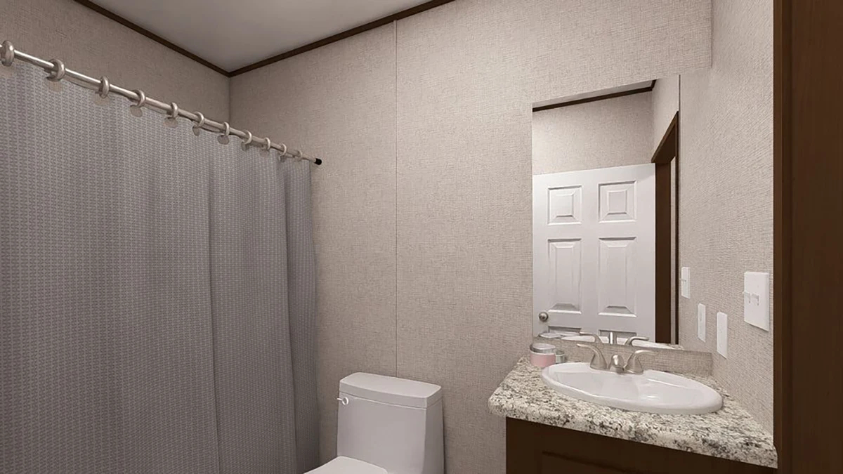9a58a450-c107-4095-8dda-465173afec64 A small bathroom with a granite countertop sink, a toilet, a wall mirror, and a shower with a gray curtain.