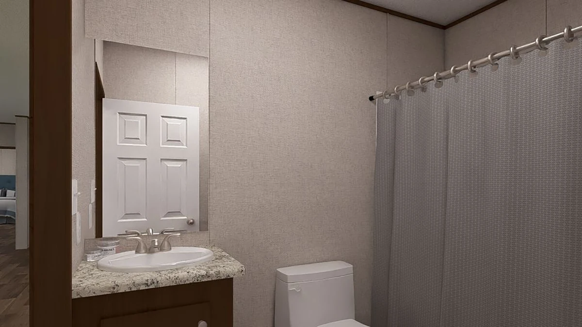 A bathroom with a sink and countertop, a wall-mounted mirror, a toilet, and a shower with a gray curtain.