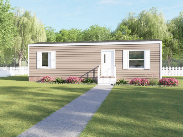 A single-story, beige manufactured home with white trim and shutters, front steps, and a path leading through a green lawn, surrounded by trees and a white picket fence.