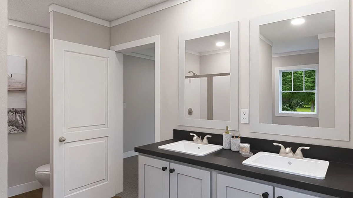 A bathroom with double sinks, two mirrors, soap dispensers, a closed door, an open door leading to a toilet, and a window showing greenery outside.