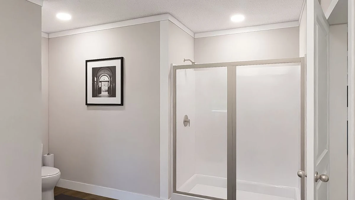 9ecf6012-5439-47f7-8241-0a090fdece51 A minimalist bathroom with a glass shower enclosure, a toilet, light gray walls, wood flooring, and a framed black-and-white photo on the wall.