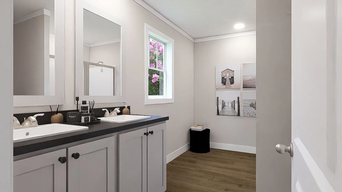 Modern bathroom with double sinks, black countertop, large mirror, wood floor, wall art, and a window showing pink flowers outside.
