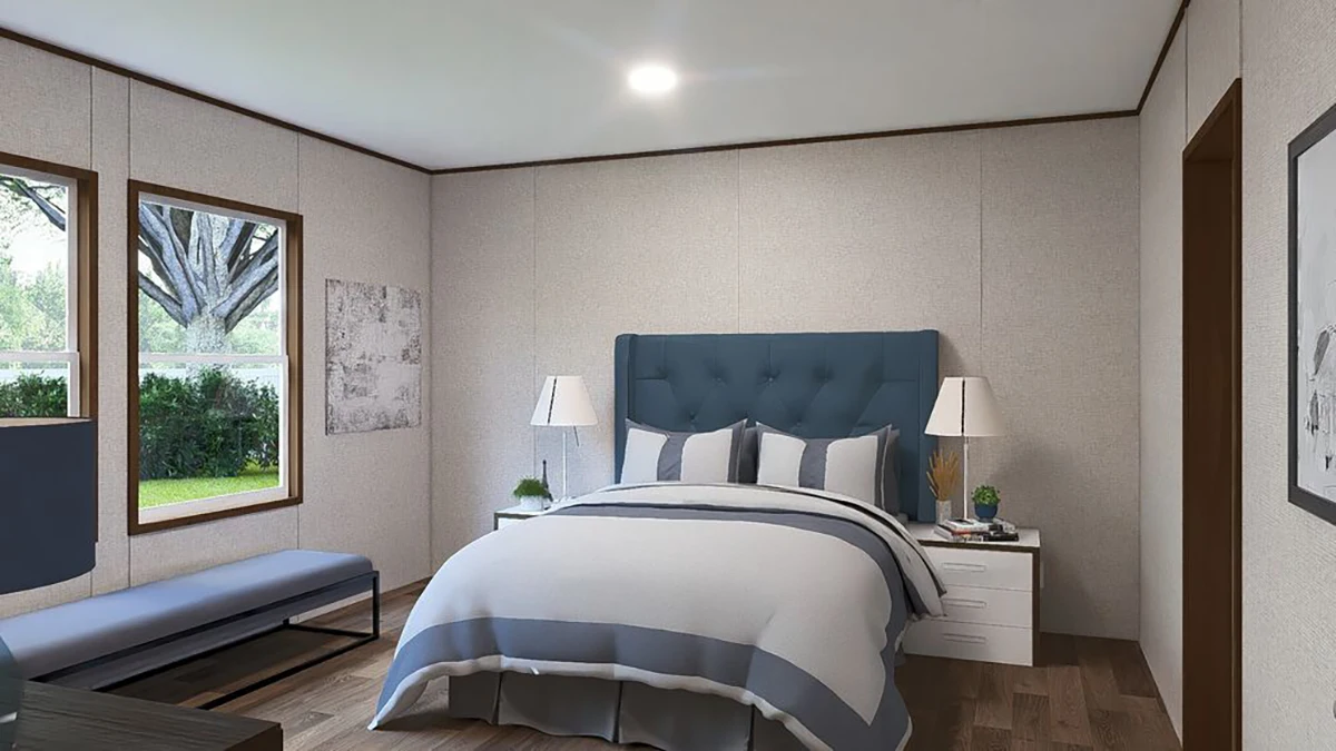 9fe75010-1963-4df7-8a37-56fe48bfaeb3 A bedroom with a blue and white bed, two bedside tables with lamps, a bench by the window, wooden floor, and neutral-colored walls.