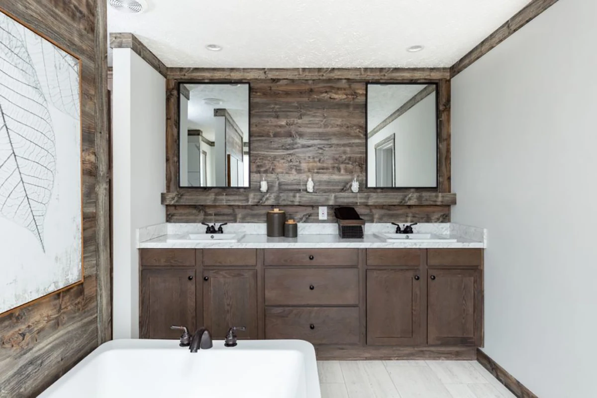 BlackIronMirror-1024×683 Modern bathroom with double sinks, wood cabinets, marble countertop, two mirrors, and a white bathtub in the foreground. Walls and accents have a rustic wood finish.