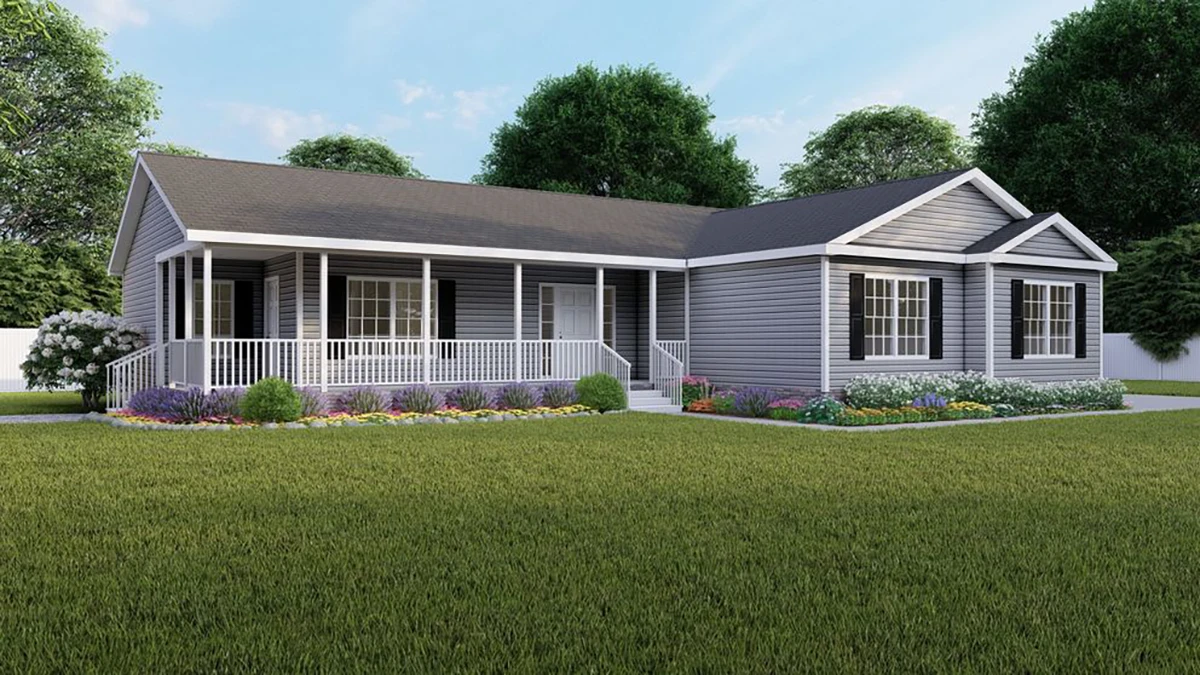 Greystone Elite 2 Single-story gray house with white trim, covered front porch, large windows, and landscaped flower beds on a well-kept lawn with trees in the background.