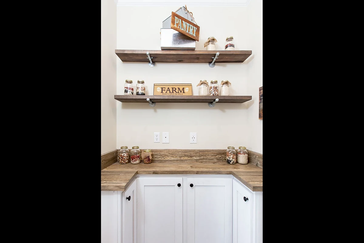 Southern Charm 12 Two wooden shelves above a countertop display jars filled with dried goods and farmhouse-themed signs; white cabinets are below the counter.