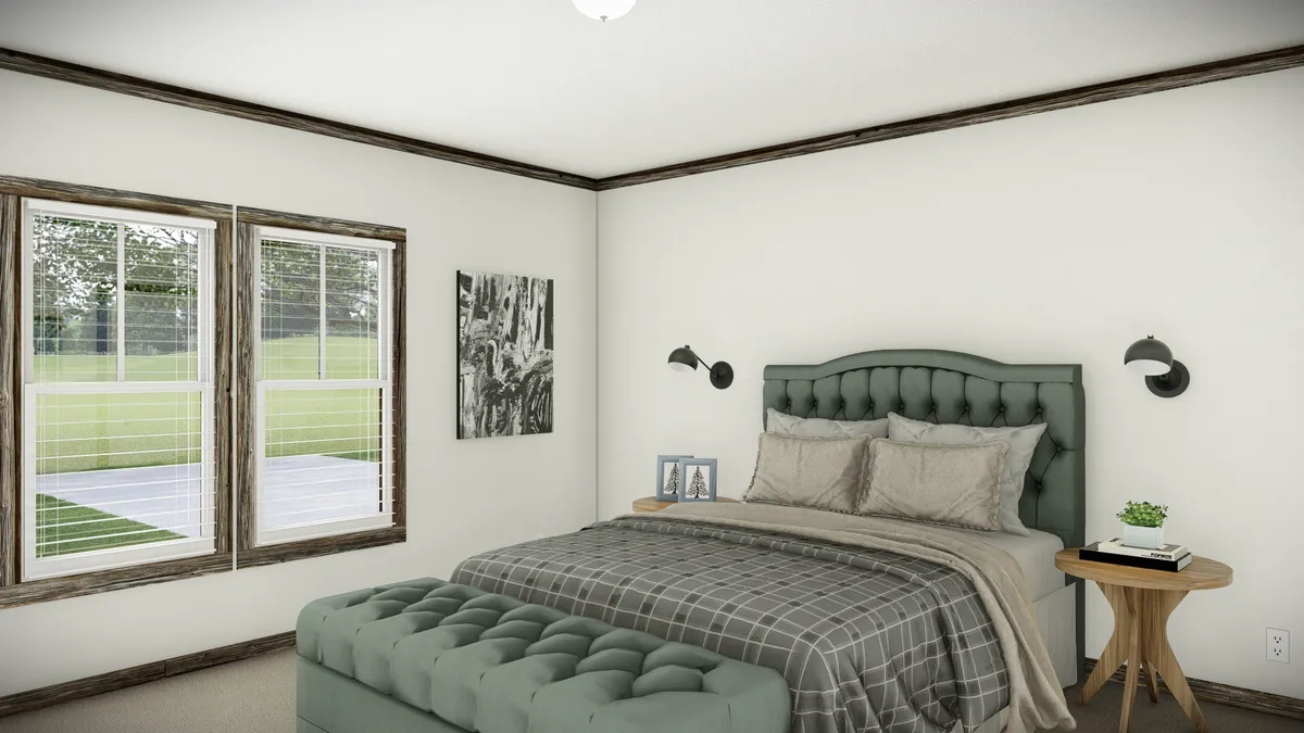 A bedroom with a green tufted bed, plaid bedding, a matching bench, side tables with lamps, framed photos, a window with blinds, and a black-and-white wall photo.