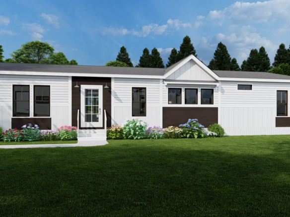 Single-story white manufactured home with dark trim, front door with steps, multiple windows, flower beds, grassy lawn, and trees in the background under a partly cloudy sky.