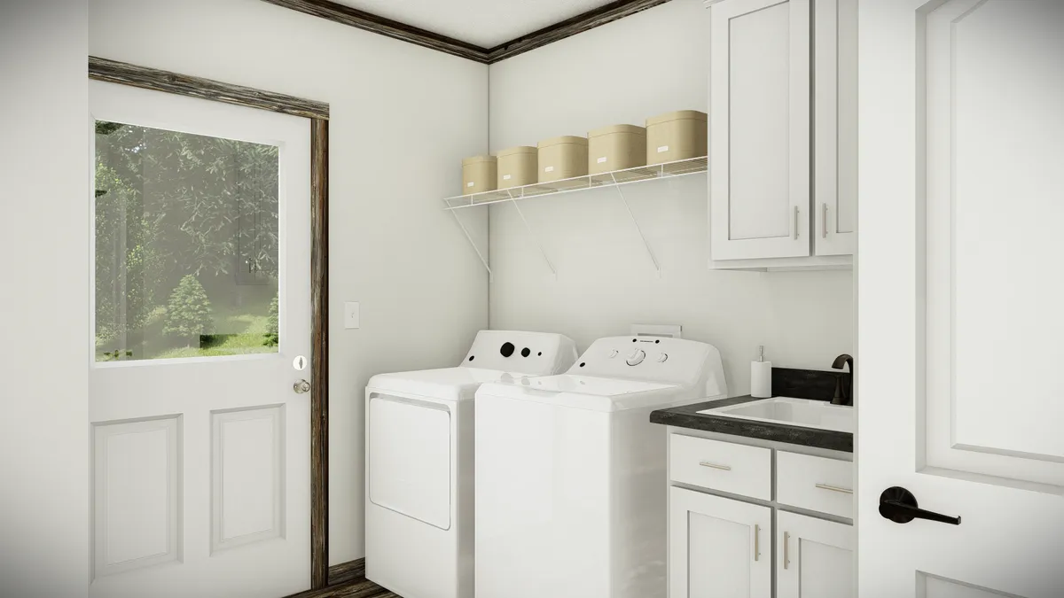 Laundry room with a washer, dryer, utility sink, white cabinets, storage bins on a shelf, and a door with a window leading outside.