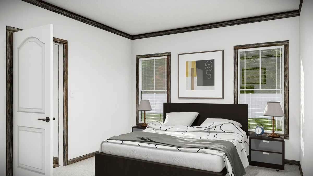 A simple bedroom with a bed, two nightstands with lamps, artwork on the wall, two windows, and an open door.
